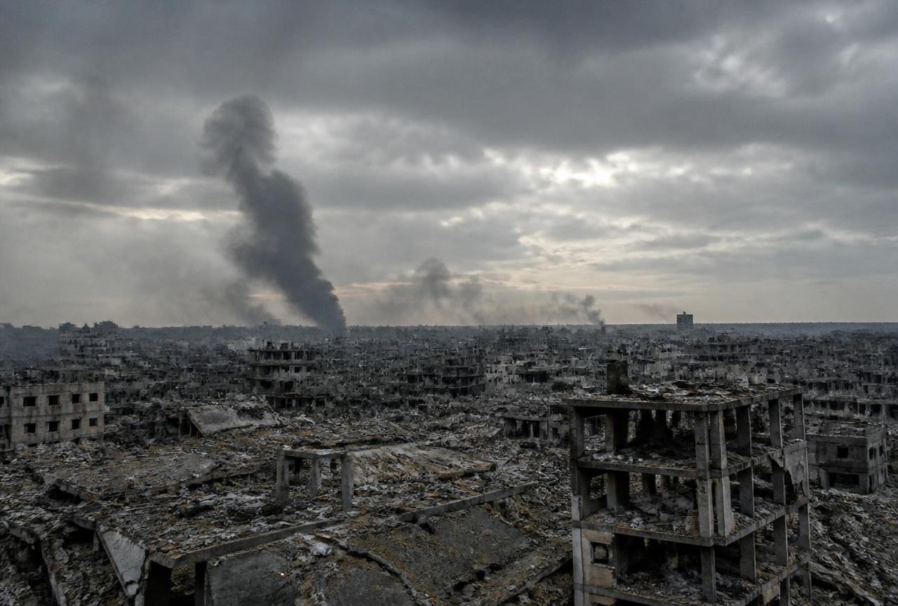 Vista amplia de una ciudad destruida con columnas de humo